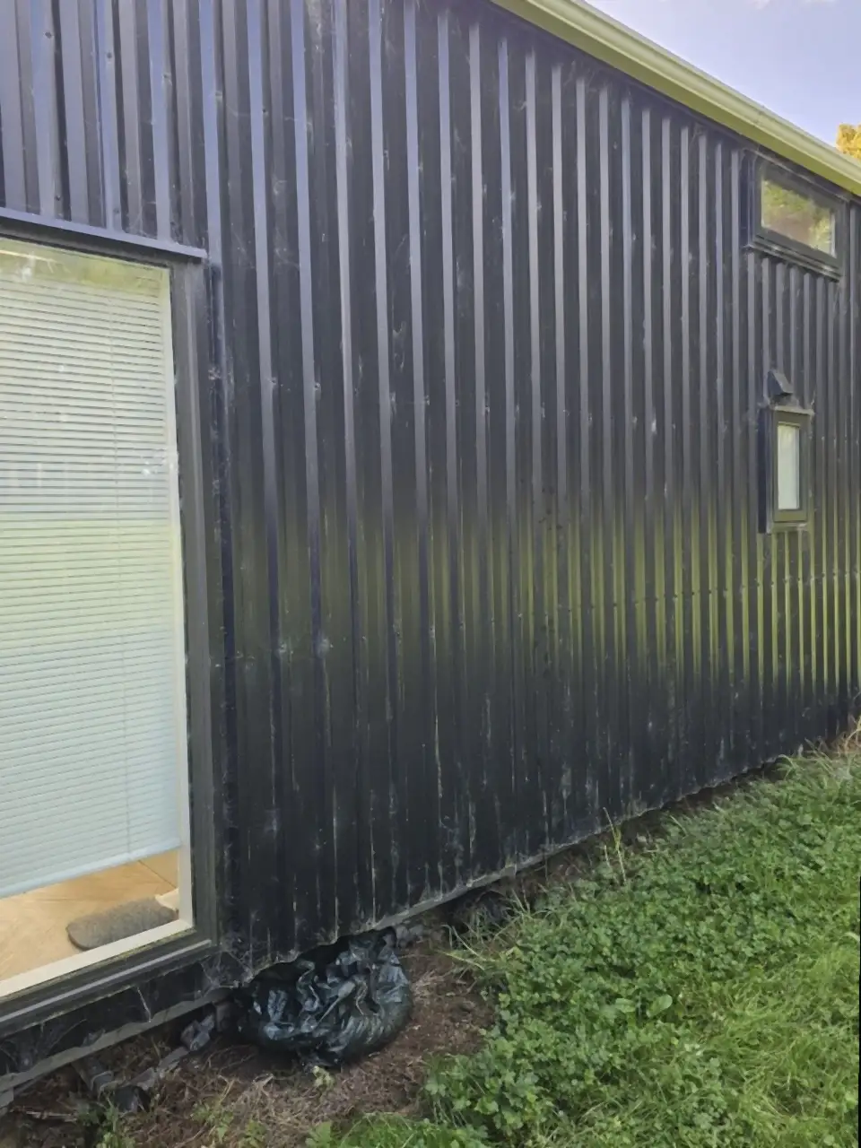Before: Dark vertical cladding beside a window, dull and dusty, with white streaks low down
