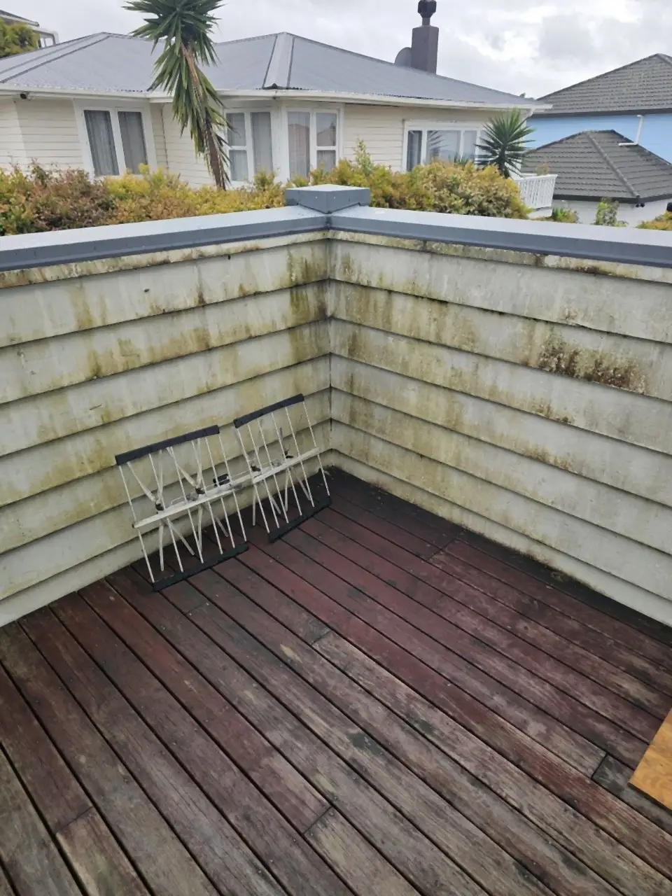 Before: A timber deck and weatherboard balustrade, green with mould