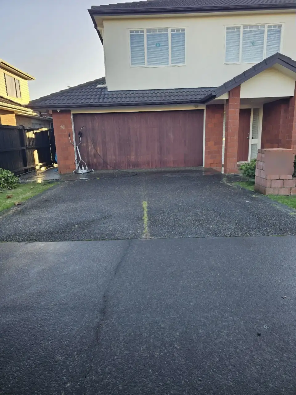 Before: A concrete drive in front of a double garage, dark and grimy, with moss along the joint
