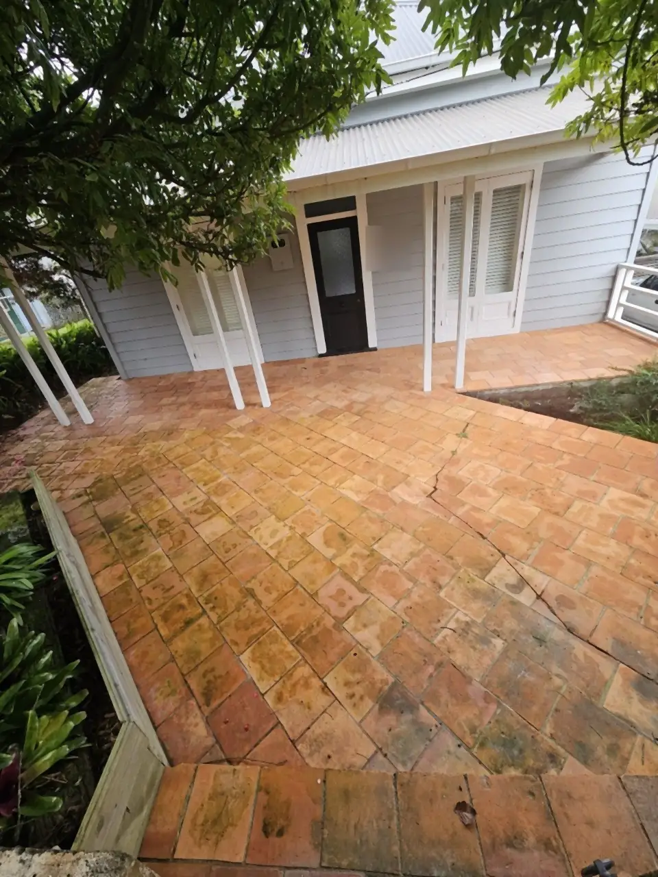 Before: A terracotta patio under a pergola, dull and green with algae