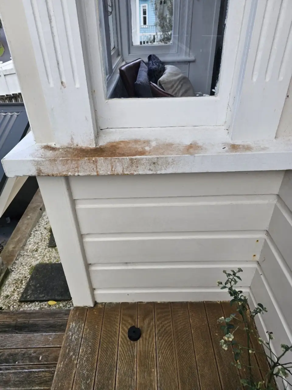 Before: A white window sill and boards streaked orange brown