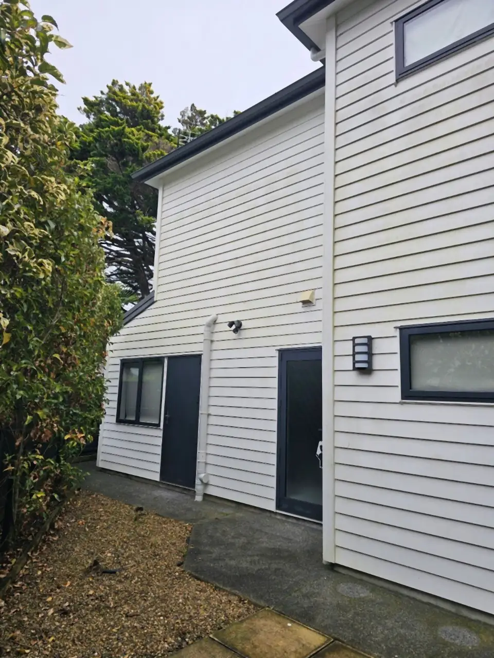 Before: The back of a two-storey weatherboard house, grey with grime