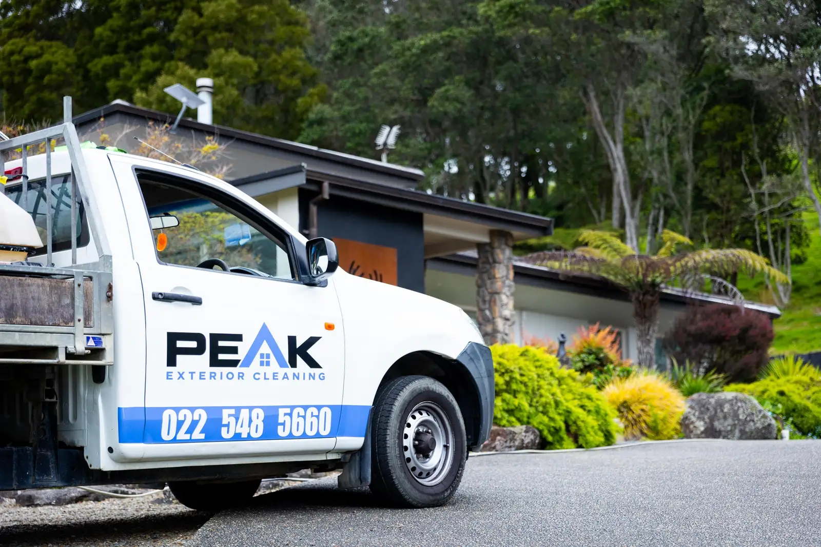 Peak's white ute side on, PEAK EXTERIOR CLEANING and 022 548 5660 along the door, a garden behind